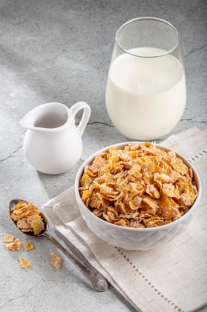 Copos de maíz en un tazón y vaso de leche en la mesa