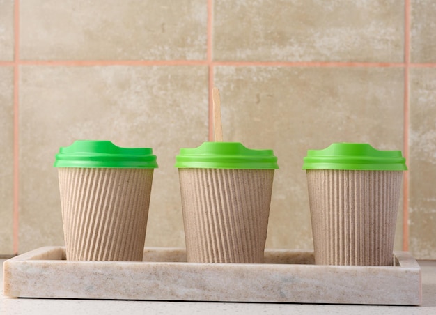 Copos marrons de papel com tampa de plástico verde para café e chá