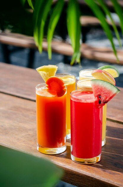 Foto copos misturados de sucos de frutas orgânicas frescas na mesa de jardim ensolarado