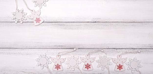 Copos de nieve y ángeles de madera rojos y blancos para el árbol de navidad en el fondo de la tabla de madera blanca