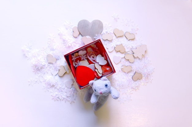 Copos de nieve artificiales, gatito de juguete y corazones decorativos rojos sobre fondo blanco suave. Decoración de Navidad y año nuevo.