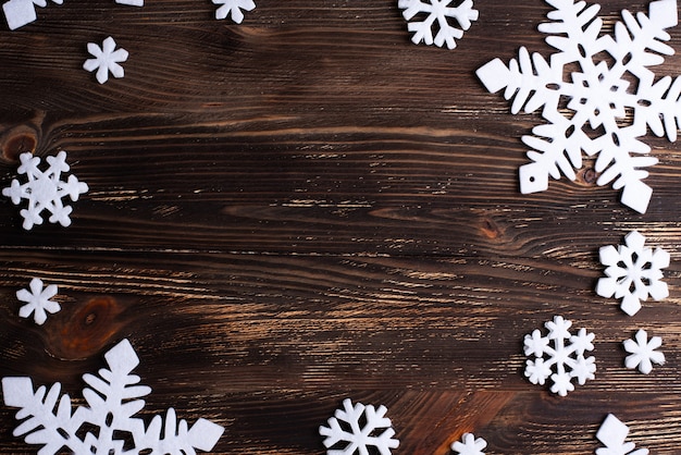 Copos de nieve blancos en forma de marco sobre un fondo de madera oscura Navidad e invierno