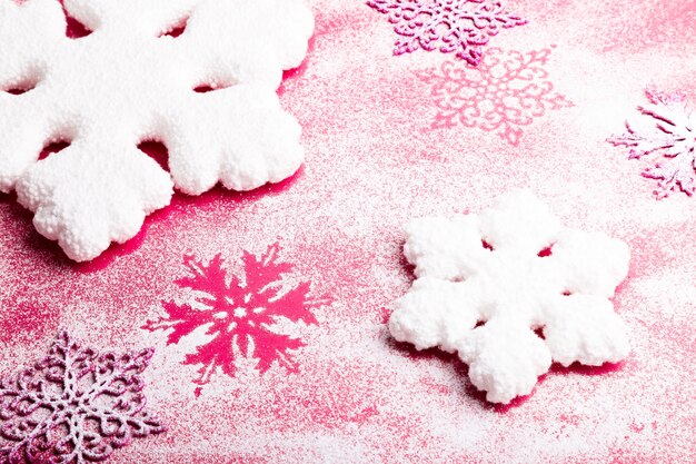 Copos de nieve de color rosa y blanco sobre un fondo rosa. Fondo de navidad Vista superior. copyspace Nieve decorativa