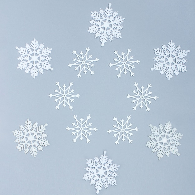 Copos de nieve decorativos blancos sobre un fondo gris. Navidad y año nuevo, un lugar para texto, minimalismo, fondo de invierno