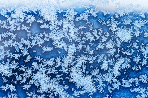 Copos de nieve y escarcha azul sobre vidrio en invierno