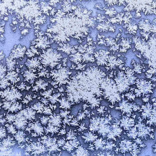 Copos de nieve y escarcha en la ventana congelada en invierno