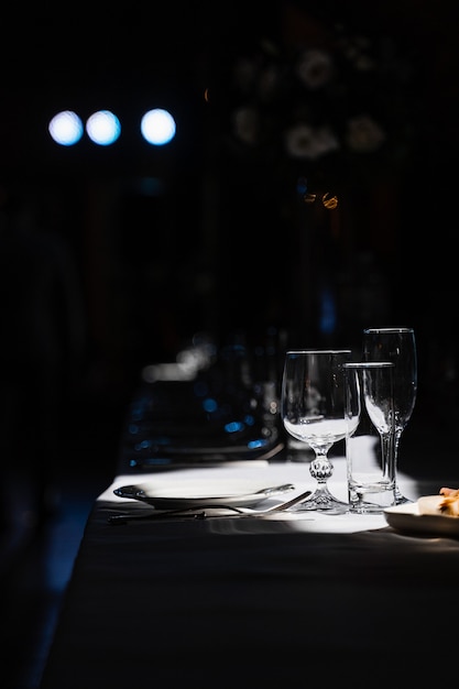 Copos, pratos e talheres em cima da mesa. Configuração de mesa no restaurante.