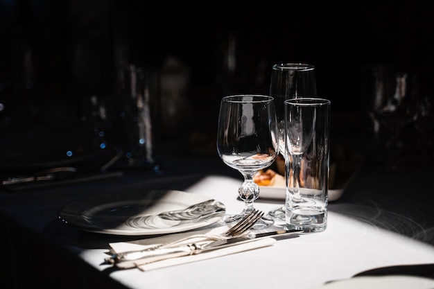 Copos, pratos e talheres em cima da mesa. Configuração de mesa no restaurante.