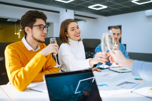 Copos tilintando com champanhe Colegas de trabalho felizes comemorando sua conquista de negócios