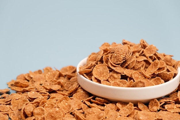 Copos de trigo duro cereal de desayuno rápido en un plato sobre un espacio de fondo azul para texto