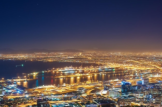 Copyspace com céu noturno escuro sobre uma paisagem urbana e vista para o mar na Cidade do Cabo, África do Sul Paisagem panorâmica cênica de luzes iluminando um horizonte metropolitano no centro da cidade à noite