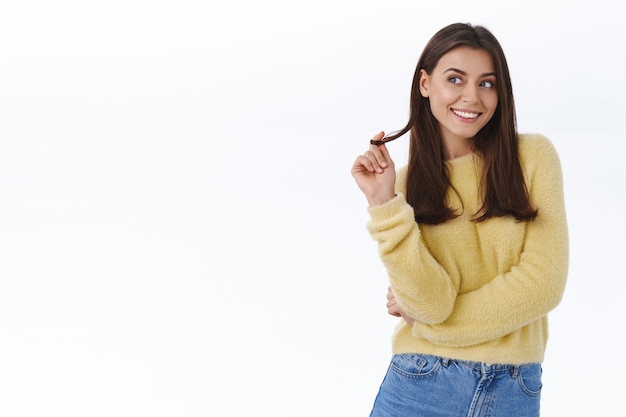 Coqueta y coqueta mujer morena linda rodando un mechón de cabello en el dedo con expresión de satisfacción soñadora, tiene una idea romántica interesante para el regalo, mira la esquina superior izquierda y sonríe sensual