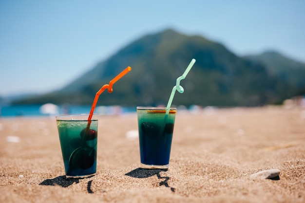 Coquetéis azuis frios frescos na praia tropical com vista para a montanha