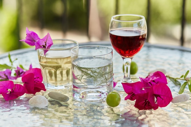 Coquetéis caseiros de verão e copo de vinho tinto flores rosa de decorações de buganvílias