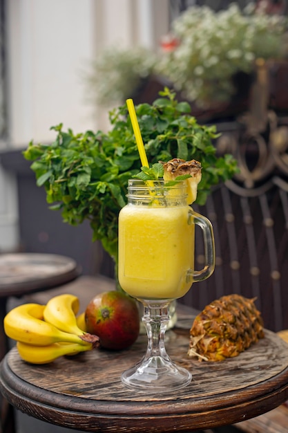 coquetéis com abacaxi, banana e manga em uma mesa de madeira