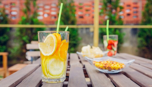 Coquetéis de água de frutas com infusão e smoothies de vegetais verdes sobre uma mesa de madeira ao ar livre. conceito de bebidas de verão orgânico saudável.