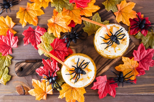 Coquetéis de halloween. suco de fruta com pedaços de maçã e gelo em copos sobre uma mesa de madeira.