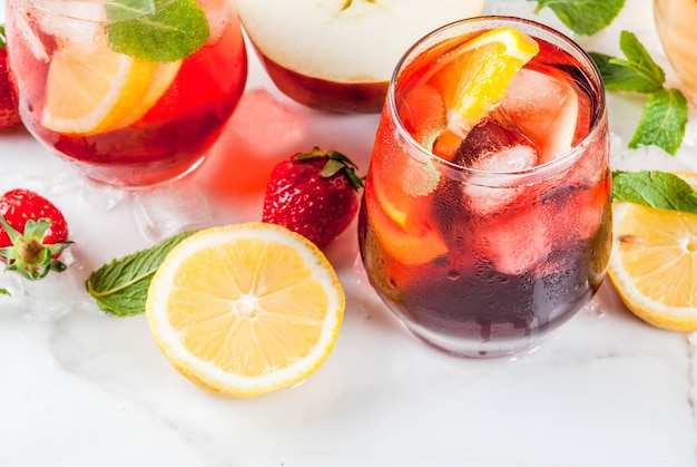 Coquetéis de sangria rosa e vermelho brancos frios com frutas frescas e hortelã.