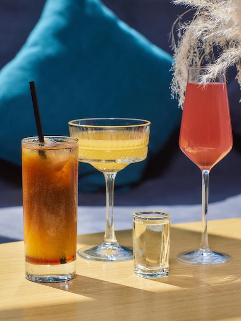 Coquetéis na mesa Bebidas coloridas diferentes em copos diferentes na mesa de madeira escura sobre fundo desfocado do restaurante Bar conceito bebidas alcoólicas