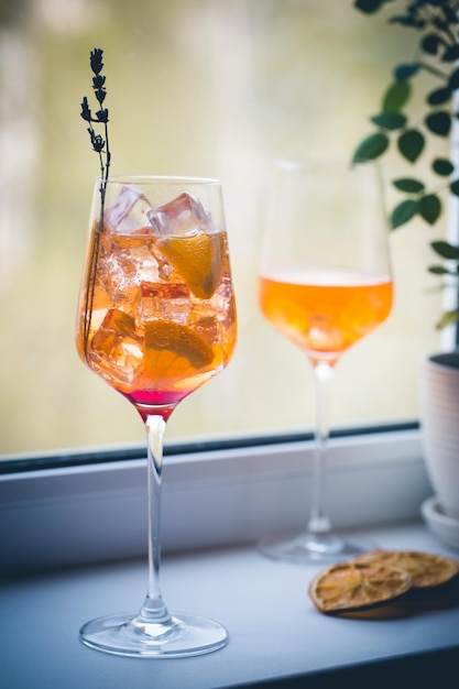 Coquetel Aperol Spritz com gelo em vidro no parapeito da janela