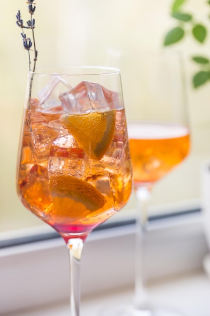 Coquetel Aperol Spritz com gelo em vidro no parapeito da janela