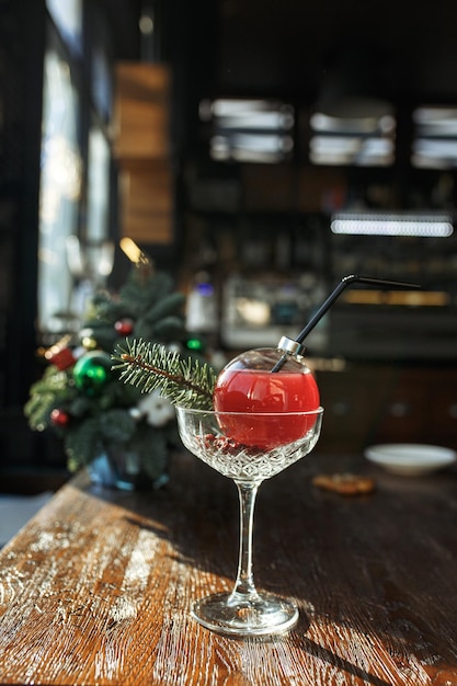 coquetel de álcool em vidro em forma de bola de natal colocada na mesa de madeira