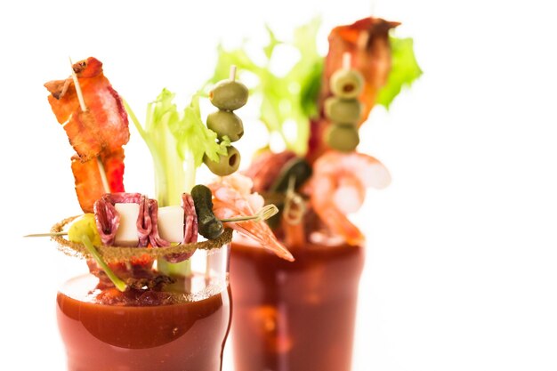 Coquetel de Bloody Mary decorado com palitos de aipo, azeitonas e tiras de bacon.