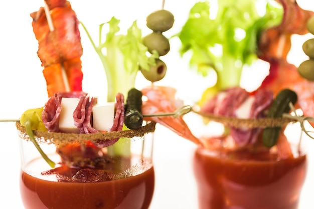 Coquetel de Bloody Mary decorado com palitos de aipo, azeitonas e tiras de bacon.