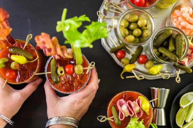 Coquetel de Bloody Mary decorado com palitos de aipo, azeitonas e tiras de bacon.