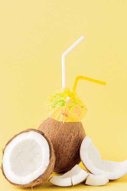 Coquetel de coco fresco com canudos em fundo amarelo