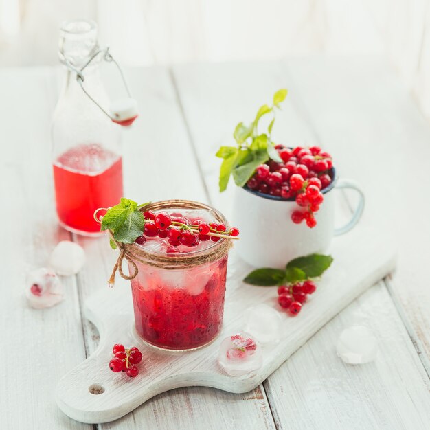 Coquetel de frutas caseiro refrescante ou ponche com champanhe, groselha, cubos de gelo e folhas de hortelã