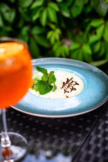 Coquetel de frutas cítricas com suco de laranja e, hortelã e gelo em um copo com gotas. Coquetel de álcool multicolorido no bar.