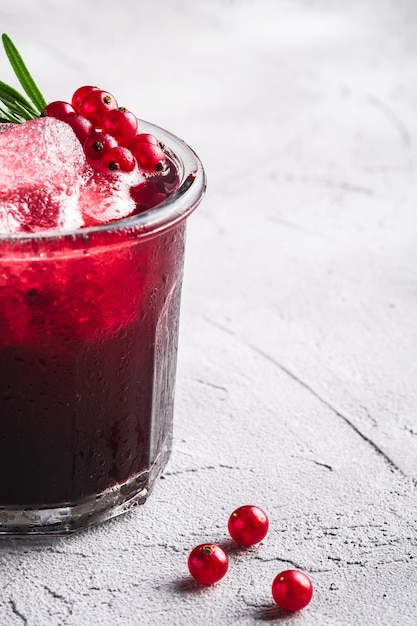 Coquetel de frutas frescas em um copo, bebida refrescante de frutas vermelhas com folha de alecrim no fundo de concreto, vista angular