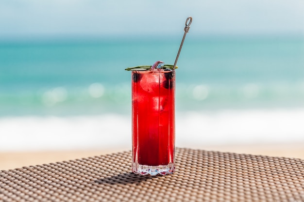 Coquetel de frutas vermelhas frescas na mesa de praia desfocado do mar turquesa no fundo