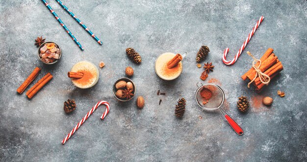 Coquetel de inverno de gemada com ovos de leite e rum escuro polvilhado com canela e noz-moscada em xícaras mesa de Natal definindo vista superior