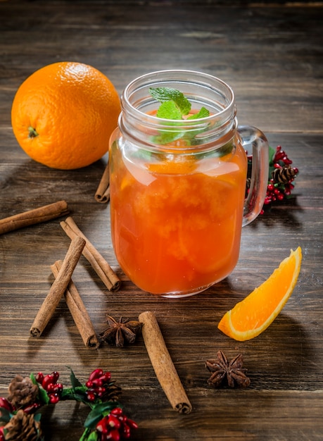 coquetel de laranja na jarra de vidro na mesa de madeira com canela