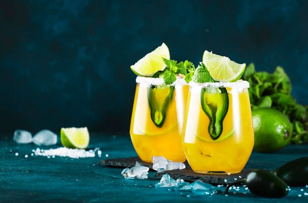 Coquetel de margarita picante com suco de tequila manga jalapeno pimenta limão e espaço de cópia de fundo azul sal