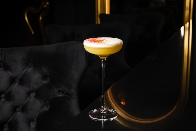 Coquetel de martini estrela pornô com maracujá e vodka no balcão do bar em ambiente escuro