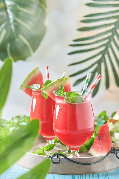 Coquetel de melancia com hortelã e gelo. Bebidas refrescantes de verão em copos na mesa de madeira azul. Conceito de alimentação saudável no verão.