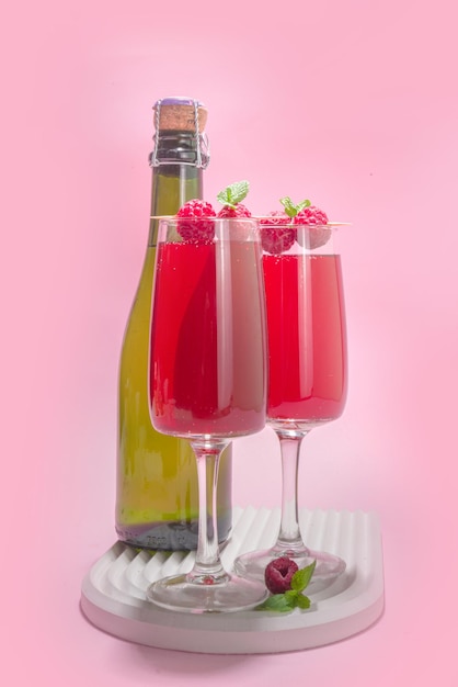 Coquetel de mimosas vermelhas. bebida clássica de mimosa com suco de framboesa, decoração com framboesa e menta. conceito de menu de bar de verão, espaço de cópia