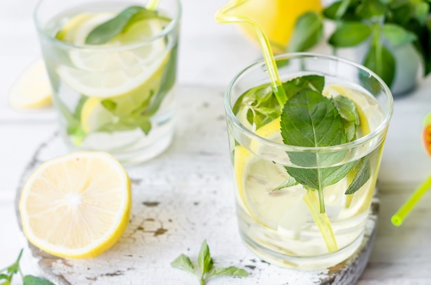 Coquetel de mojito em copo, limão e folhas de hortelã na cesta na mesa de madeira branca,