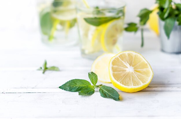 Coquetel de mojito em copo, limão e folhas de hortelã na cesta na mesa de madeira branca,