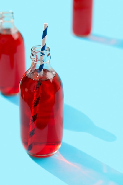 Coquetel de ponche cranberrie gelado de verão em garrafa com fundo azul