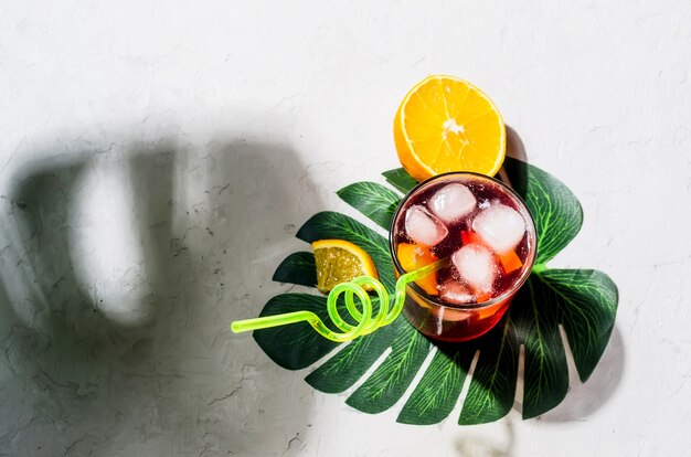 Coquetel de sangria vermelha caseira de verão com laranja e gelo em um copo de pedra cinza de concreto