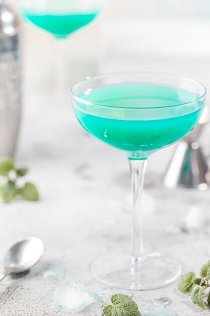 Coquetel de verão colorido Blue Hawaii ou bebida alcoólica de lagoa azul gelada com hortelã em fundo de pedra clara