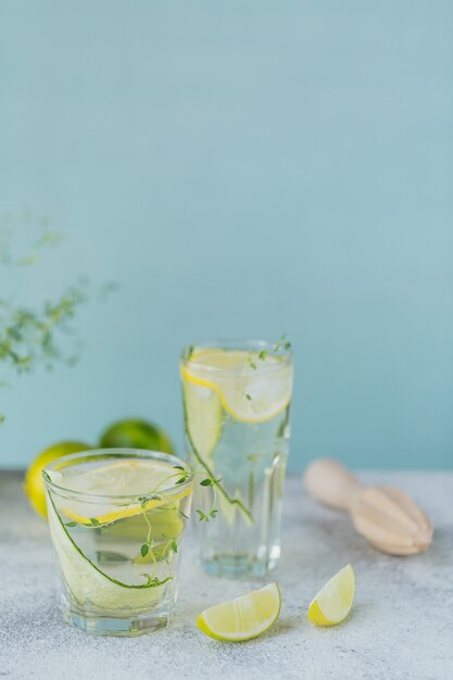 Coquetel de verão com pepino, limão, tomilho e cubos de gelo em madeira