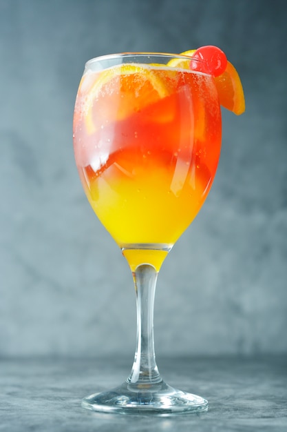 Coquetel de verão. suco de laranja com hortelã, syrop, fatias de frutas e cereja com gelo.