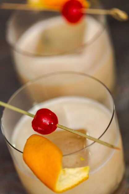 Coquetel de whisky sour decorado com laranja e cereja.