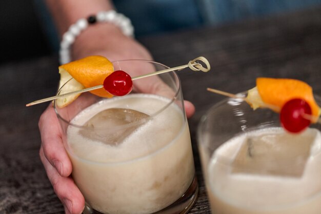 Coquetel de whisky sour decorado com laranja e cereja.