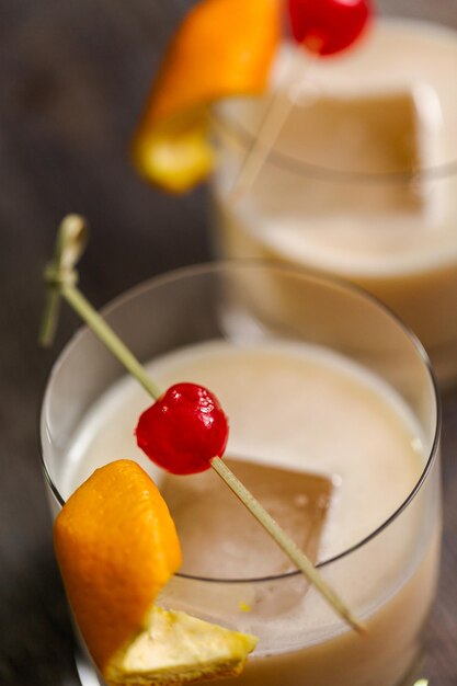 Coquetel de whisky sour decorado com laranja e cereja.